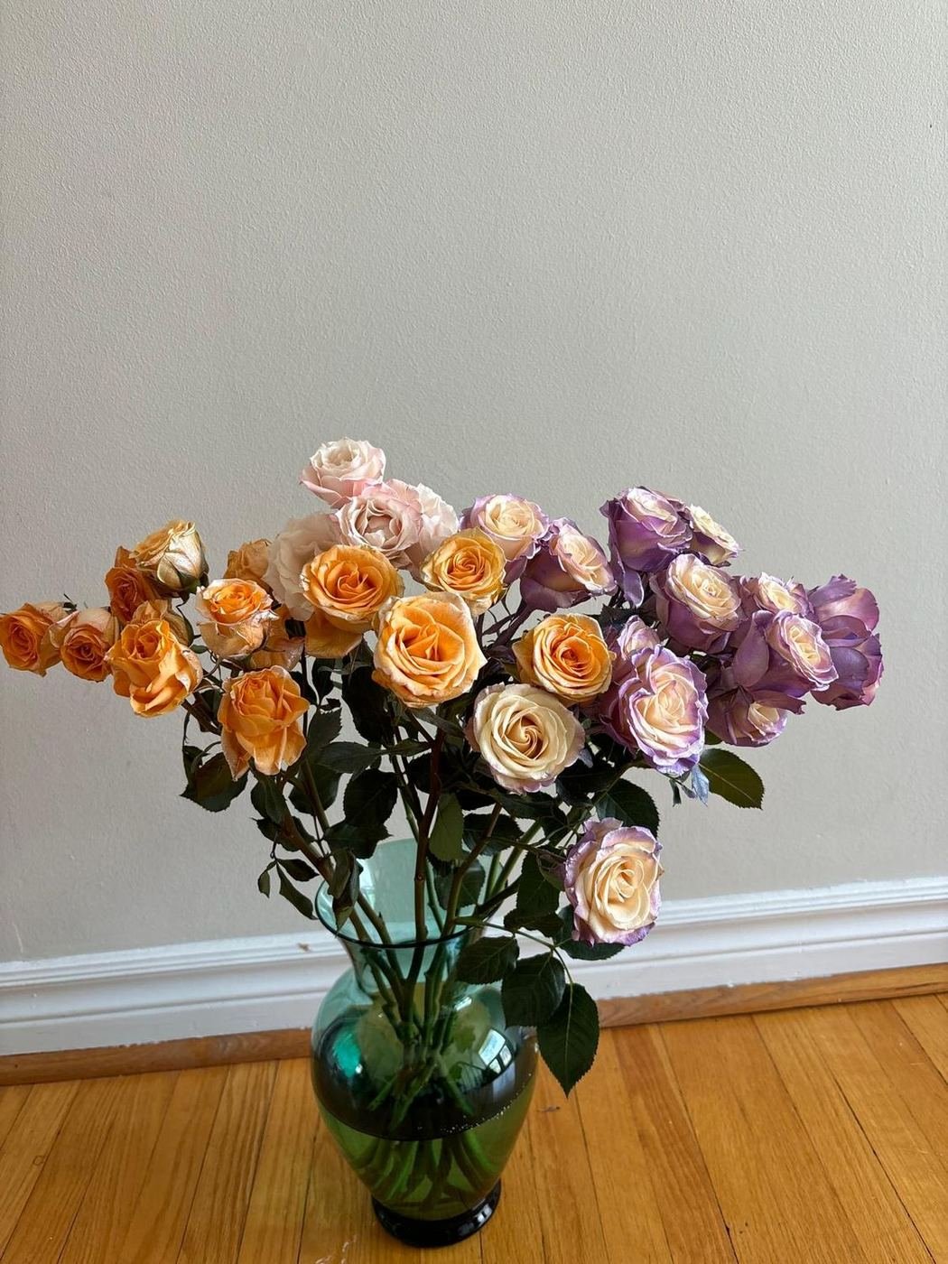 Peach and lavender garden roses in a sea-green glass vase