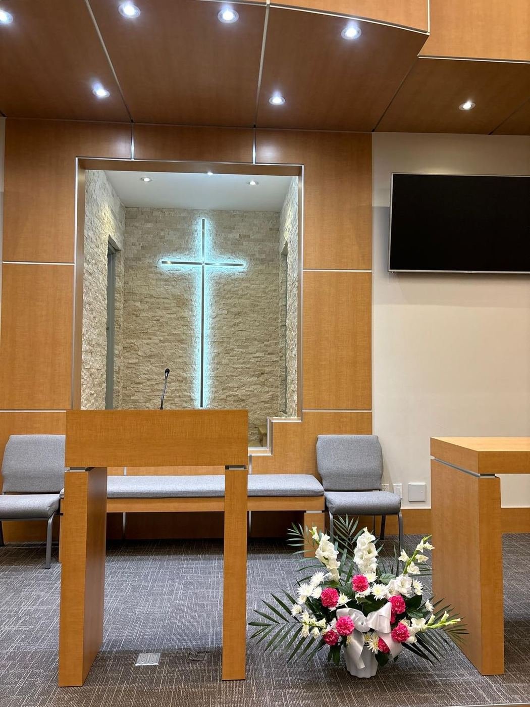White gladiolus and pink carnation arrangement placed at the front of a chapel
